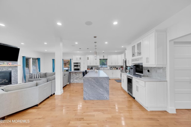 kitchen with beverage cooler, open floor plan, recessed lighting, and white cabinetry