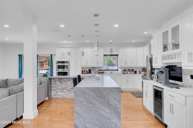 kitchen featuring tasteful backsplash, open floor plan, a center island, stainless steel double oven, and wine cooler