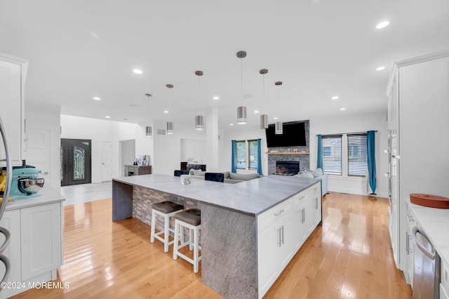 kitchen with light wood-style flooring, stainless steel dishwasher, open floor plan, and white cabinetry