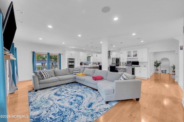 living room with wine cooler, recessed lighting, light wood-style floors, and arched walkways