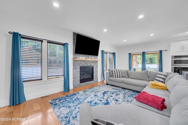 living room with recessed lighting, light wood-type flooring, visible vents, and a fireplace