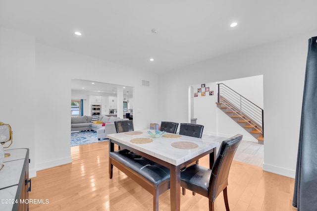 dining room with light wood finished floors, visible vents, baseboards, stairs, and recessed lighting