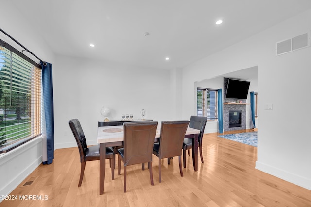 dining area featuring light wood-type flooring, visible vents, a glass covered fireplace, and recessed lighting