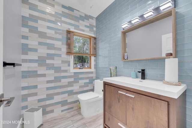 bathroom with toilet, tile walls, and vanity