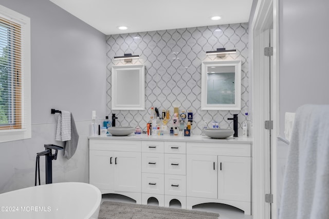 full bathroom with double vanity, a soaking tub, tile walls, and a sink