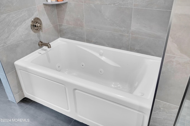 bathroom featuring tile patterned floors, a jetted tub, and tile walls