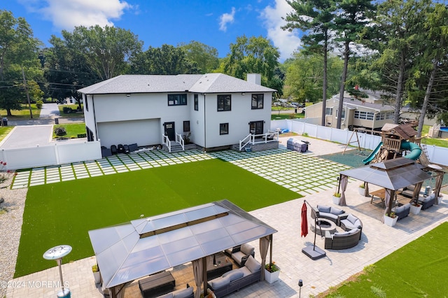 back of property with a patio area, an outdoor living space with a fire pit, a playground, and a fenced backyard