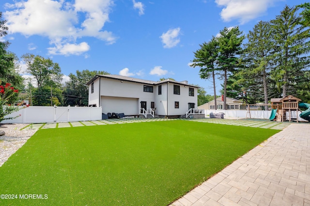 view of yard featuring a playground, a gate, a fenced backyard, and a garage