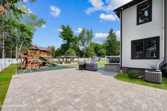 view of patio / terrace featuring a gazebo, a playground, central AC, and fence