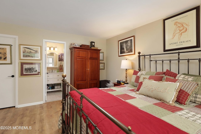 bedroom with baseboards, ensuite bath, and light wood-style flooring