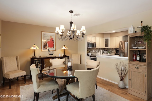 dining space with light wood-type flooring, visible vents, and a chandelier