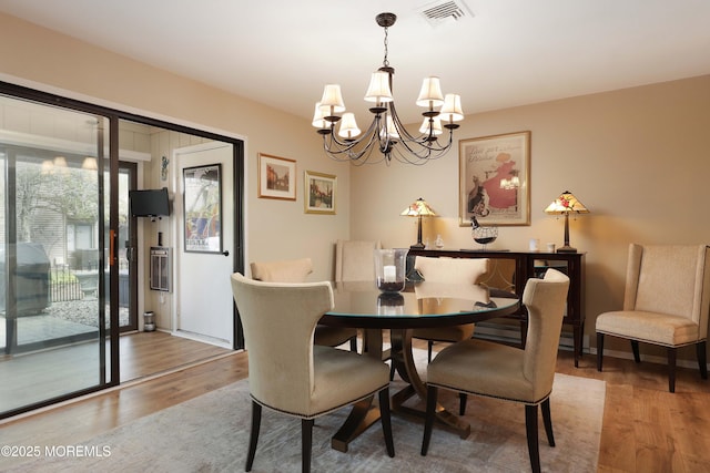 dining space featuring an inviting chandelier, wood finished floors, and visible vents