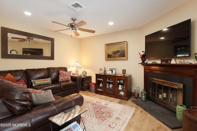 living area with visible vents, wood finished floors, a glass covered fireplace, recessed lighting, and ceiling fan