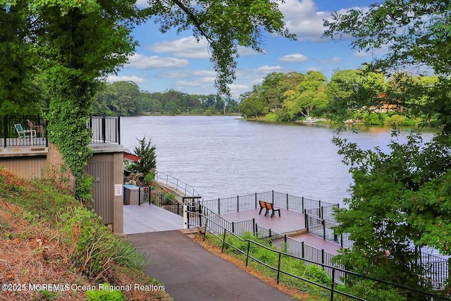 property view of water featuring fence and a boat dock