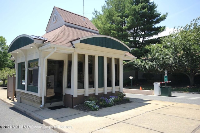 exterior space with roof with shingles and a sunroom