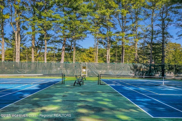 view of tennis court featuring community basketball court and fence