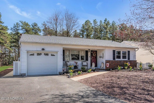 single story home featuring brick siding, covered porch, a garage, and driveway