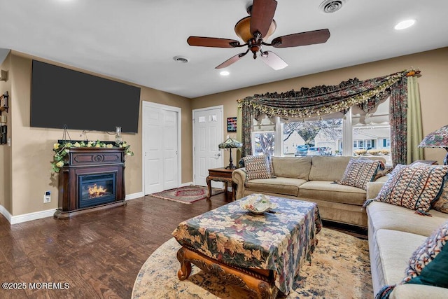 living area with baseboards, wood finished floors, visible vents, and ceiling fan