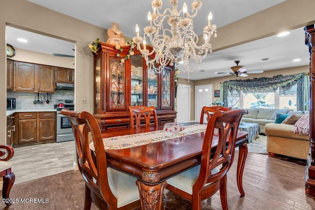 dining space with recessed lighting, light wood-style flooring, and ceiling fan with notable chandelier
