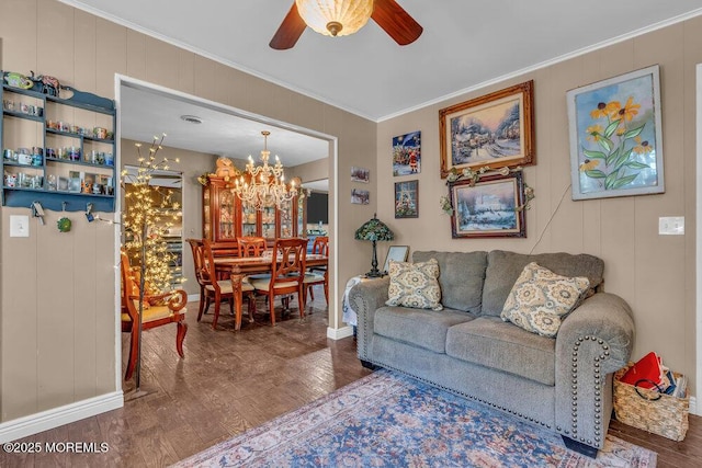 living area featuring ceiling fan with notable chandelier, crown molding, baseboards, and wood finished floors