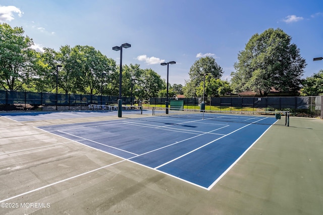 view of tennis court featuring community basketball court and fence