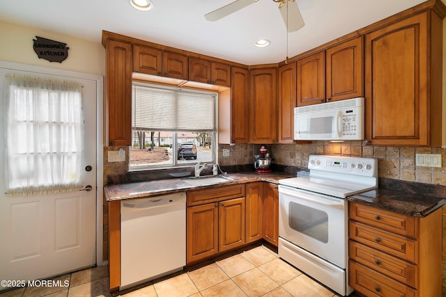 kitchen featuring tasteful backsplash, white appliances, brown cabinetry, and a sink