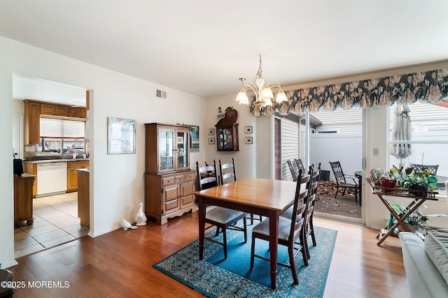 dining space featuring an inviting chandelier, light wood-style floors, and visible vents