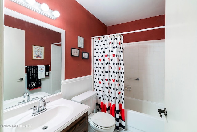 bathroom with a wainscoted wall, toilet, shower / bath combo, and vanity