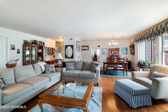 living area with an inviting chandelier, light wood-style flooring, and visible vents