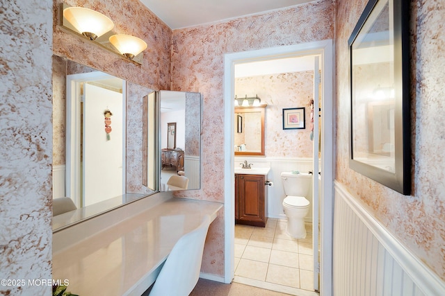 bathroom featuring tile patterned flooring, wallpapered walls, a wainscoted wall, toilet, and vanity