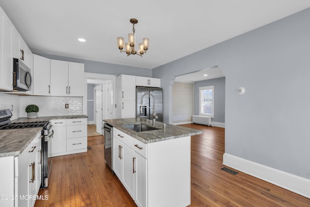 kitchen with a sink, radiator, stainless steel appliances, and dark wood-style flooring