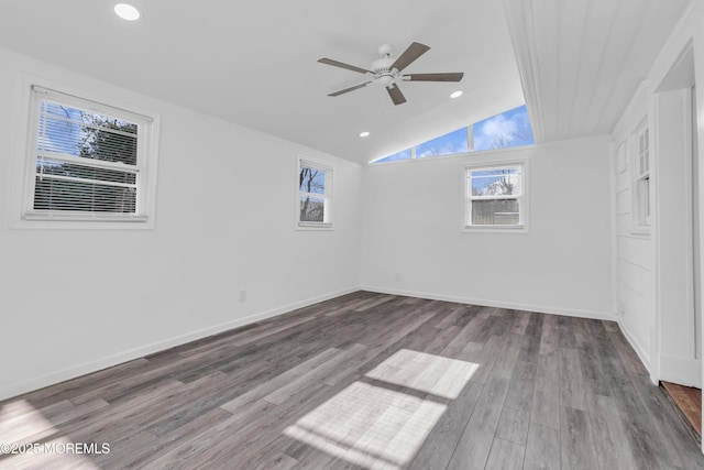 empty room featuring lofted ceiling, wood finished floors, baseboards, and ceiling fan