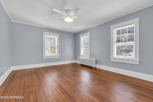 empty room with plenty of natural light, radiator heating unit, baseboards, and hardwood / wood-style floors