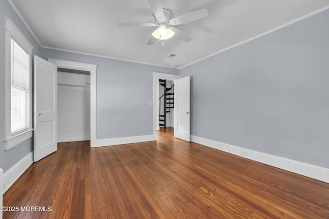 unfurnished bedroom featuring visible vents, baseboards, ornamental molding, a closet, and wood-type flooring