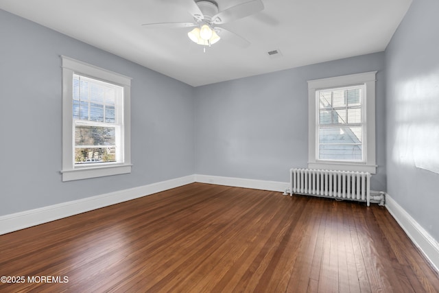 unfurnished room featuring hardwood / wood-style flooring, radiator, baseboards, and plenty of natural light