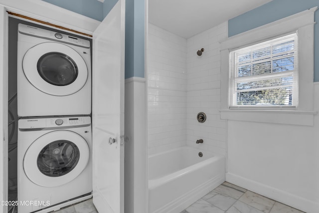 full bath featuring  shower combination, stacked washer / dryer, baseboards, and marble finish floor