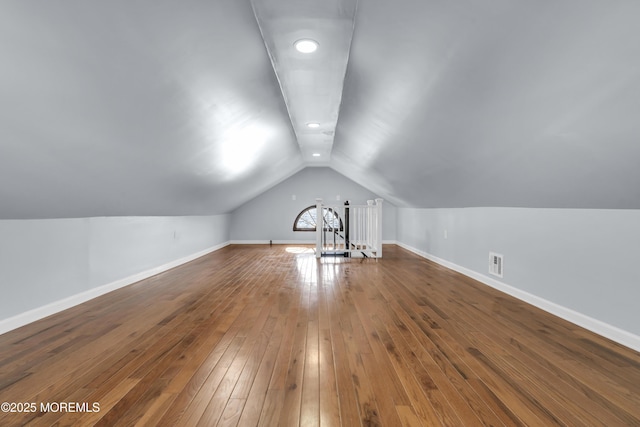 additional living space with vaulted ceiling, visible vents, baseboards, and hardwood / wood-style floors