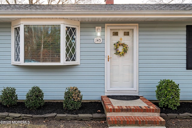 property entrance with a shingled roof and a chimney