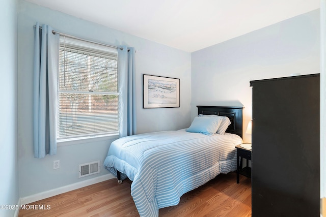 bedroom featuring visible vents, baseboards, and wood finished floors