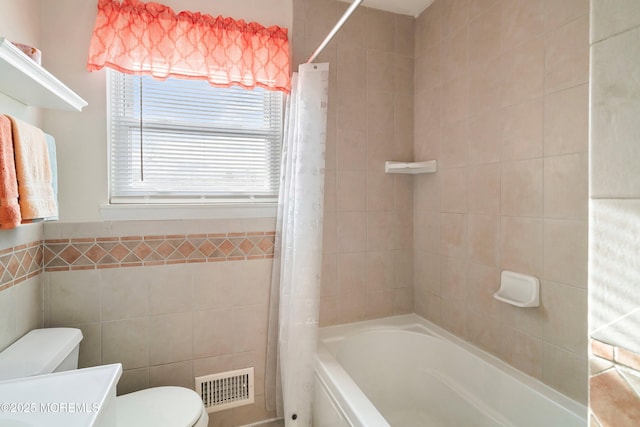 full bath featuring visible vents, toilet, shower / bath combo, tile walls, and vanity