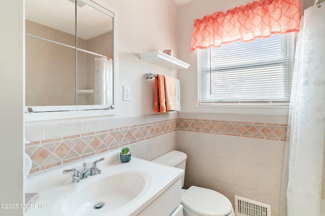 bathroom with vanity, visible vents, curtained shower, tile walls, and toilet