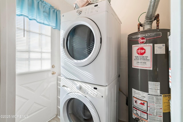 washroom with stacked washer and clothes dryer, water heater, and laundry area