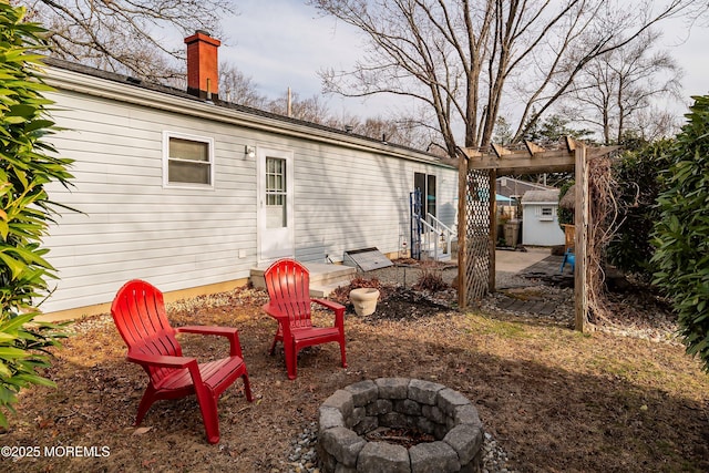 rear view of property with a patio area, entry steps, a chimney, and an outdoor fire pit