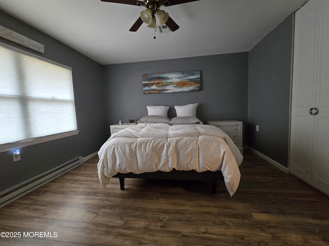 bedroom featuring a baseboard heating unit, baseboards, dark wood-type flooring, and a ceiling fan