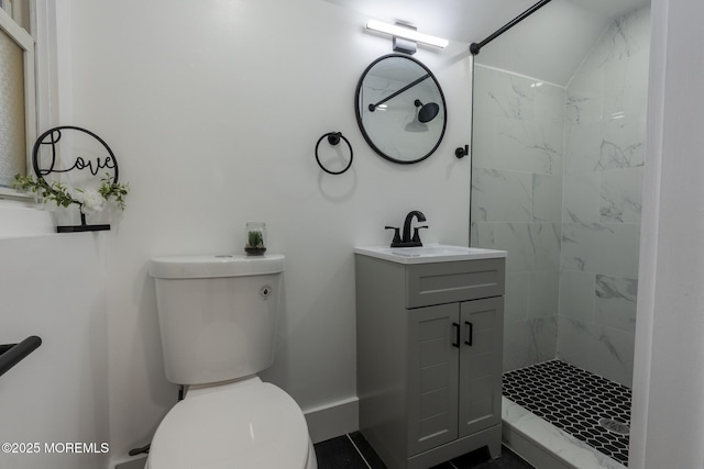 full bath featuring baseboards, toilet, vanity, and a tile shower