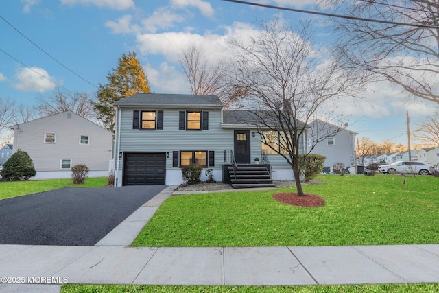 tri-level home with driveway, an attached garage, and a front lawn