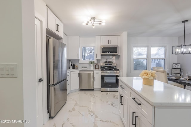 kitchen featuring a notable chandelier, a sink, tasteful backsplash, stainless steel appliances, and light countertops