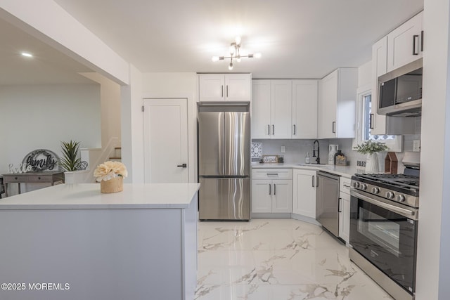 kitchen featuring marble finish floor, a sink, appliances with stainless steel finishes, white cabinets, and light countertops