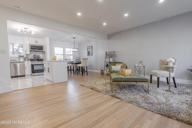 living room with a notable chandelier, recessed lighting, baseboards, and light wood-style floors