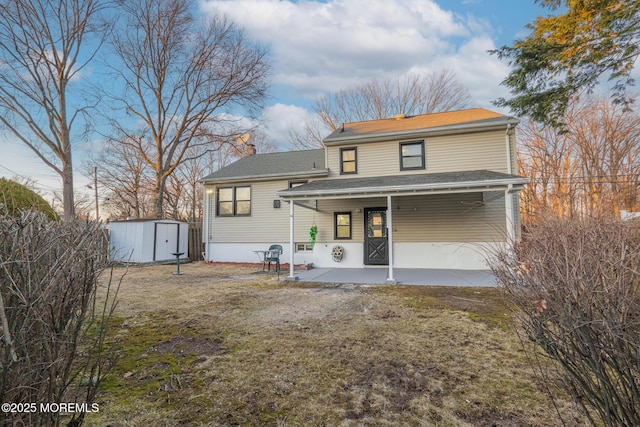 rear view of property with a storage shed, a patio area, an outdoor structure, and roof with shingles